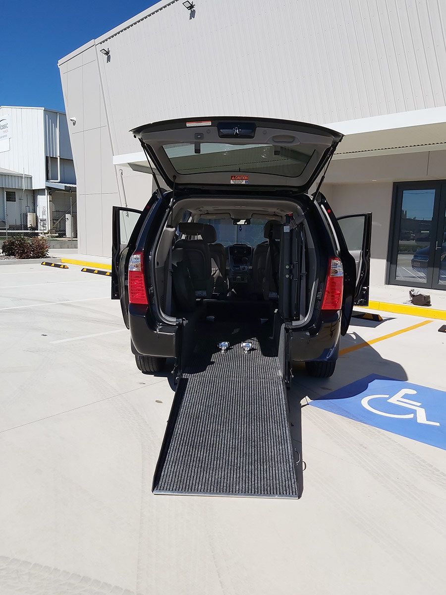 A Black Car with A Ramp in The Back Is Parked in A Handicapped Parking Spot — Mobility Modification Services In Garbutt, QLD