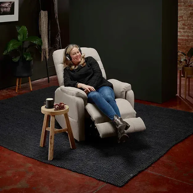 A Lady Sitting On A Cream Leather Recliner In A Living Room — Mobility Modification Services In Garbutt, QLD