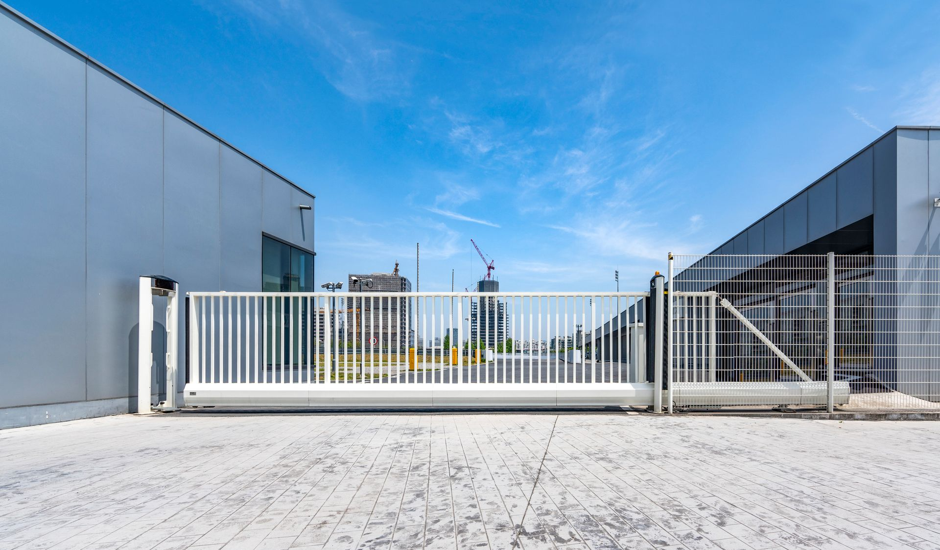 Gray metal fence with an orange light on top, with trees in the background.