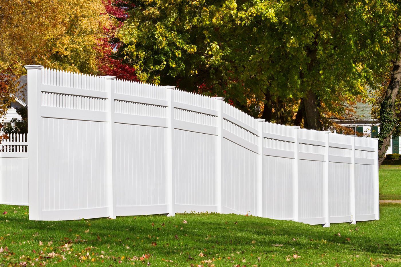 Stainless steel gate and fence with stone pillars against a green landscape.