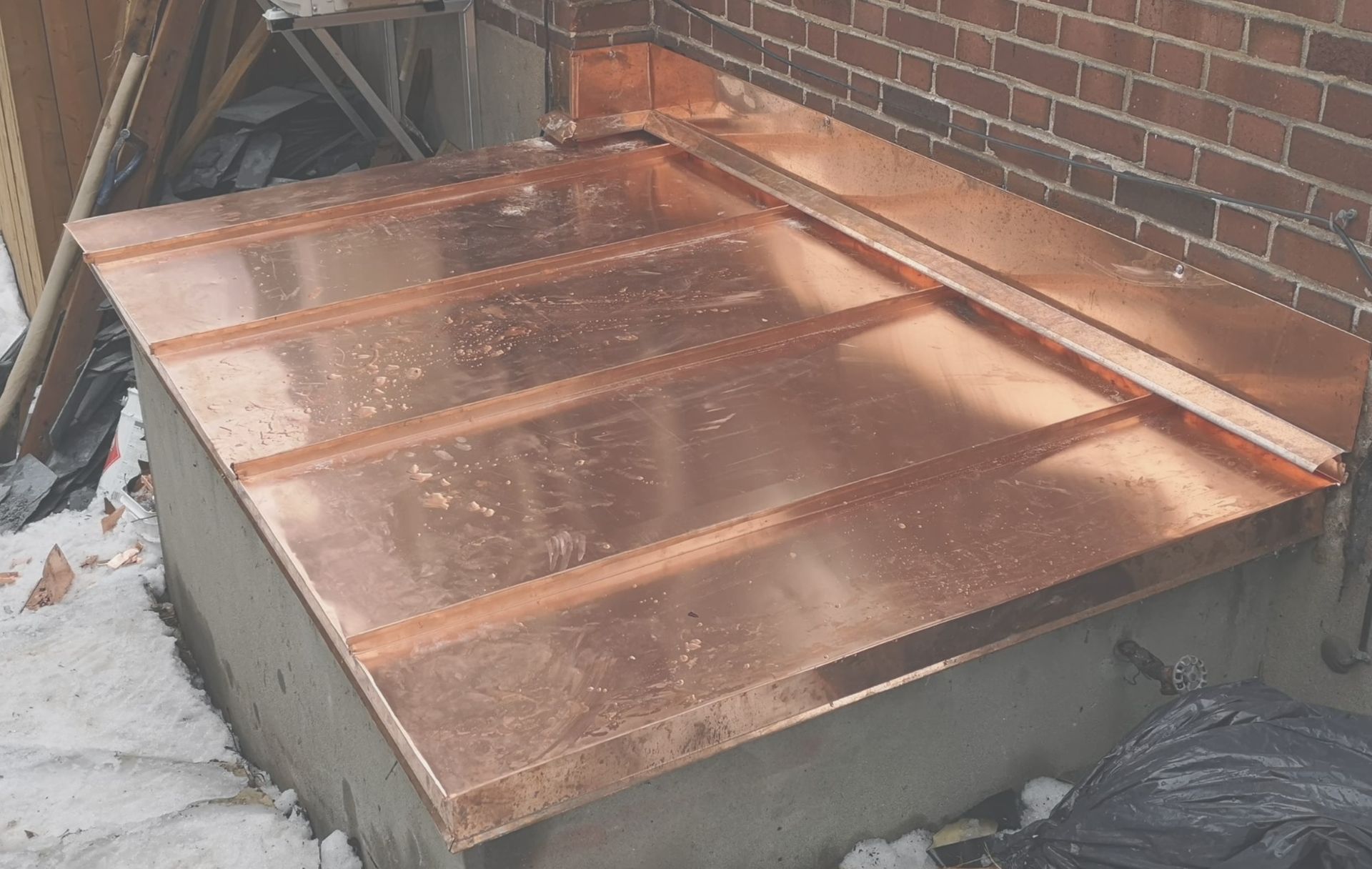 Un toit en cuivre est en cours d'installation sur le côté d'un bâtiment en briques.