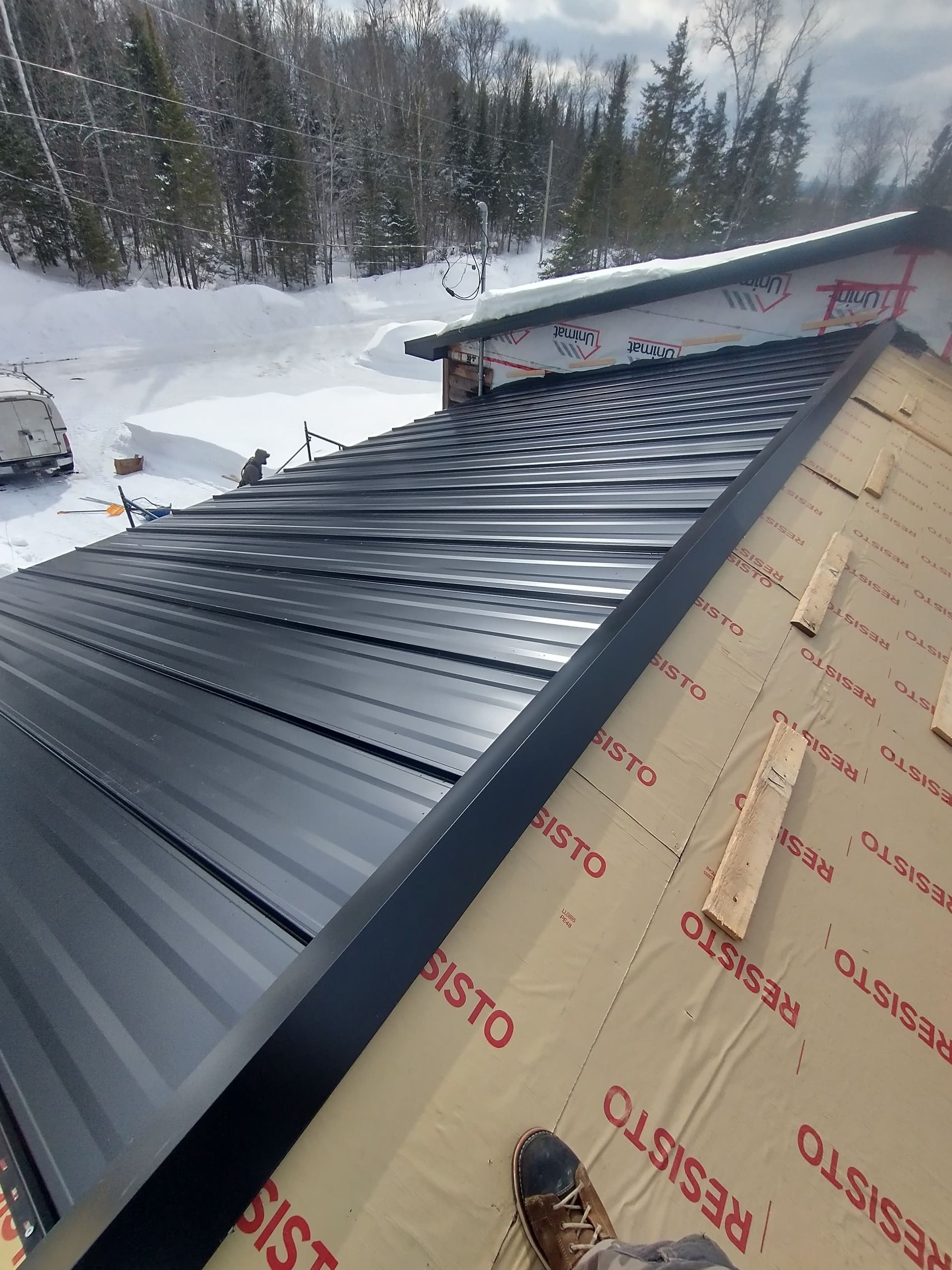 Un toit en métal noir est en cours d'installation sur une maison