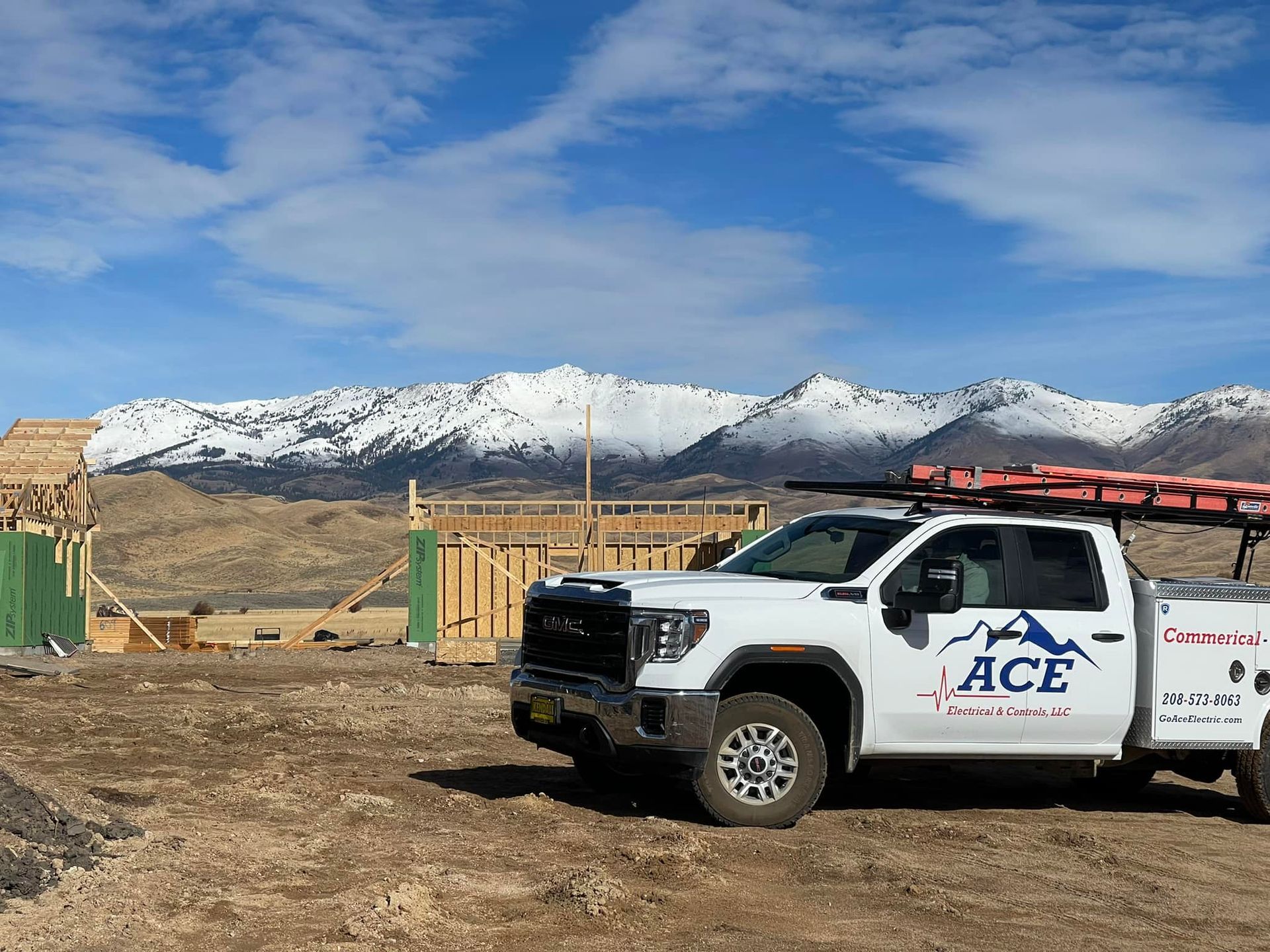 White ACE Power & Solar truck at a construction site with mountains in the background under a blue sky.