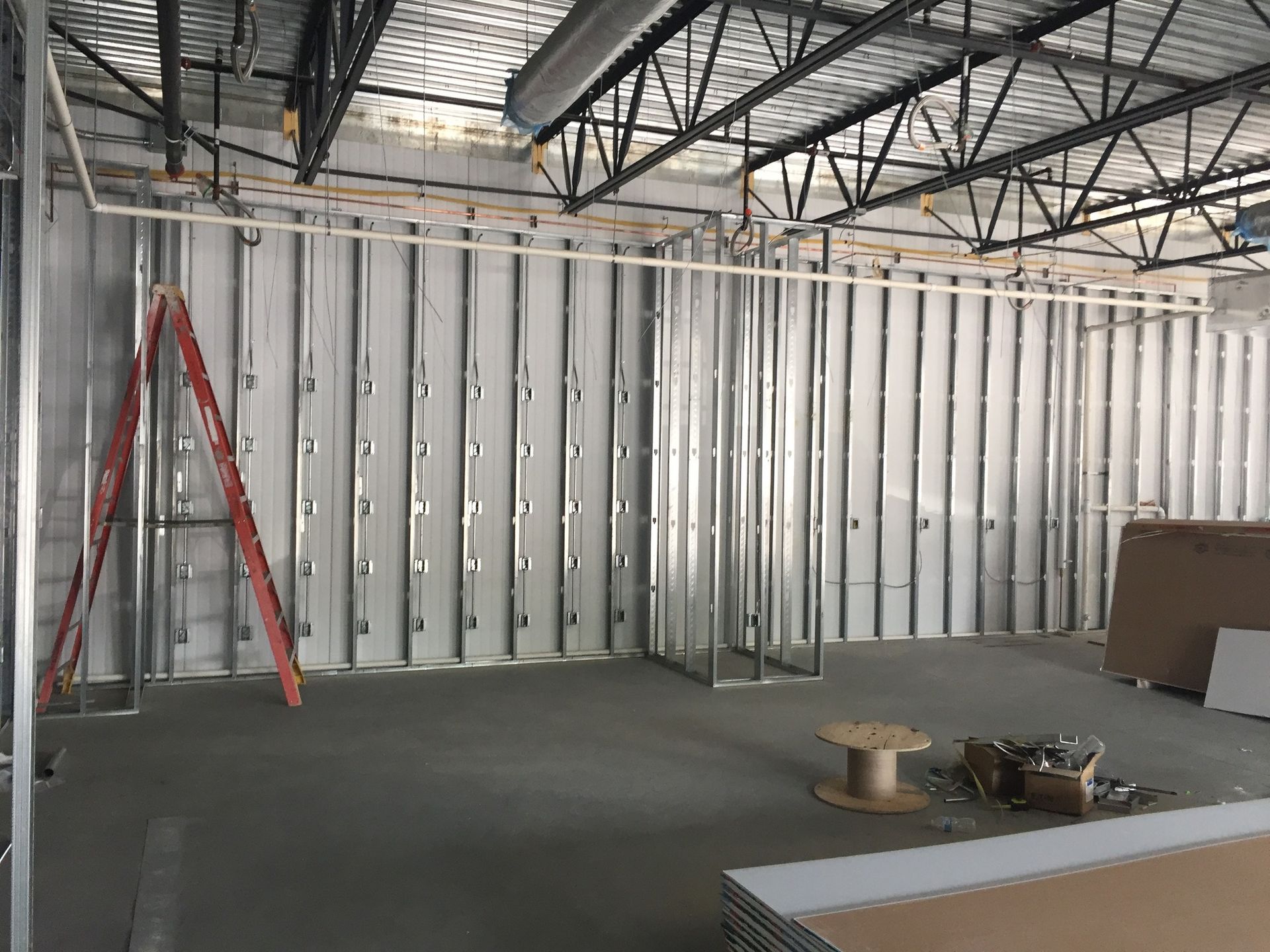 Interior construction: Metal studs form wall frames, with ladder and materials present.