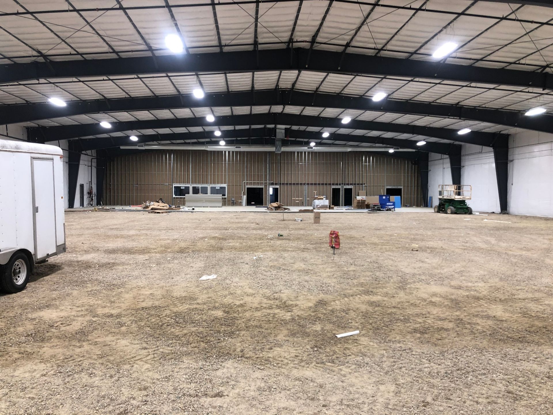 An empty, unfinished industrial building with a gravel floor and exposed wooden framing.