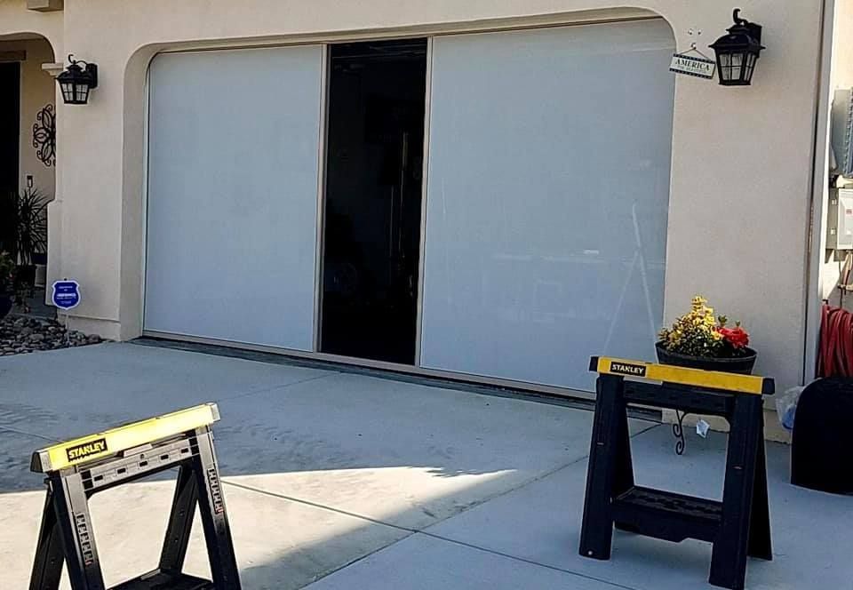 A garage door is open and a workbench is sitting in front of it.