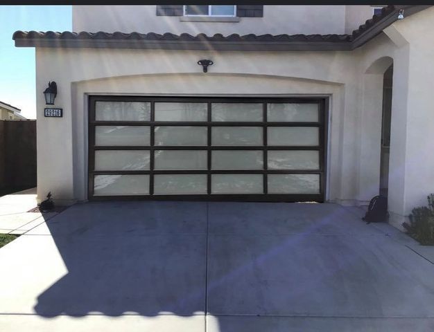 A white house with a black garage door and a shadow on the ground