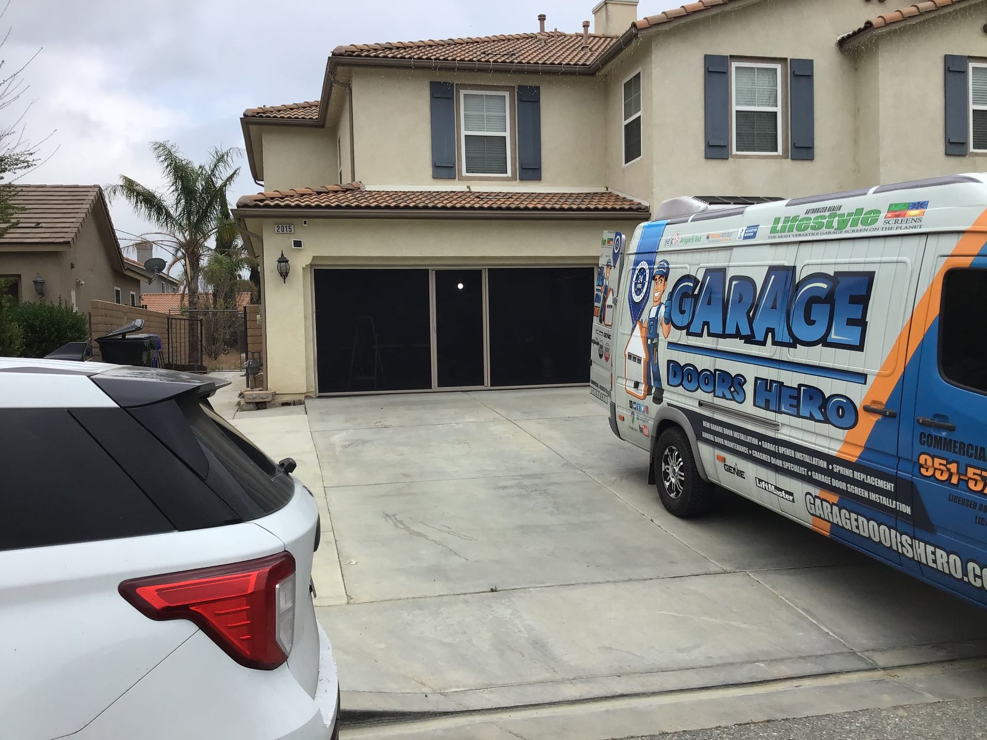 A garage door company van is parked in front of a house.