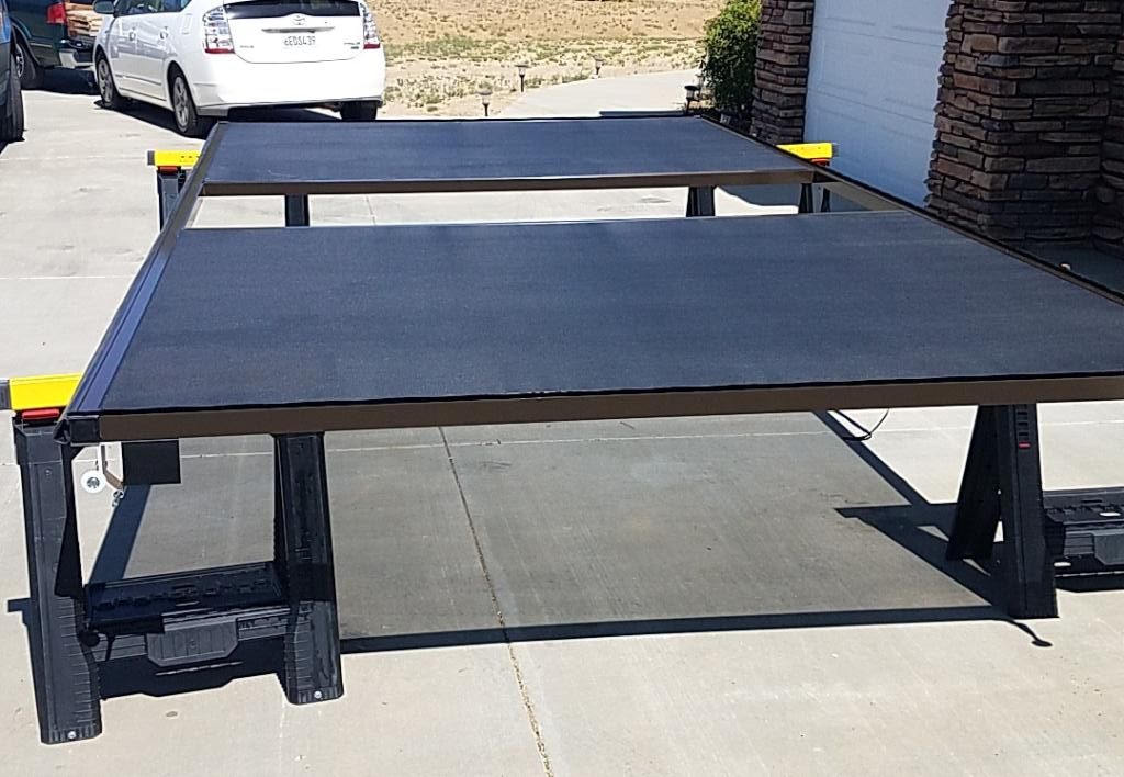 A large black table is sitting in a driveway next to a car.
