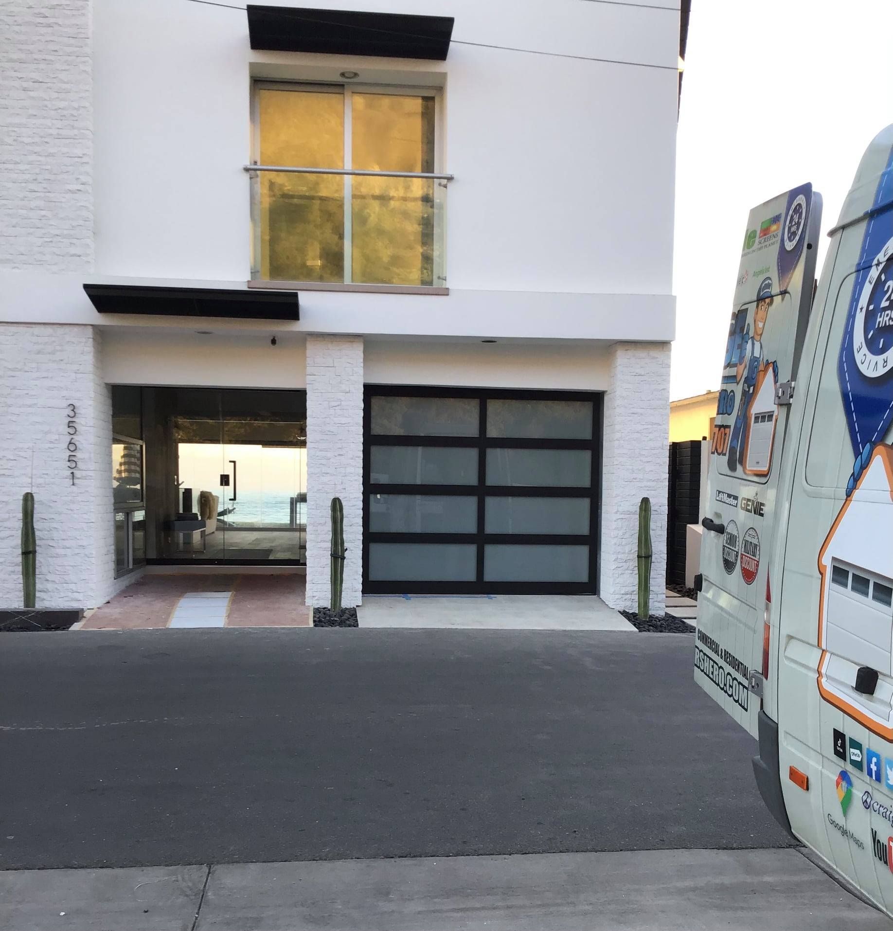 A white building with a blue van parked in front of it