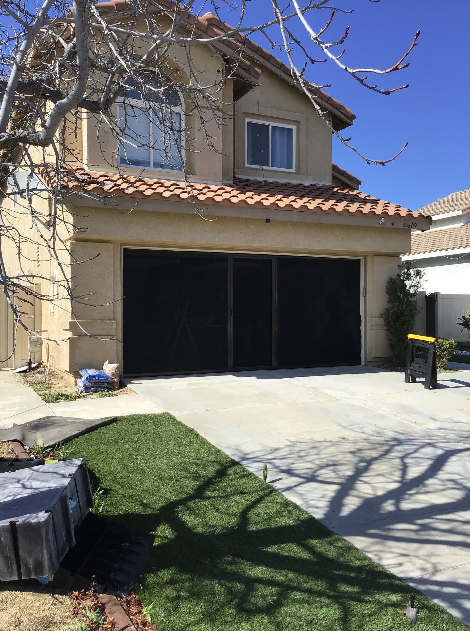 A house with a black garage door and a tree in front of it
