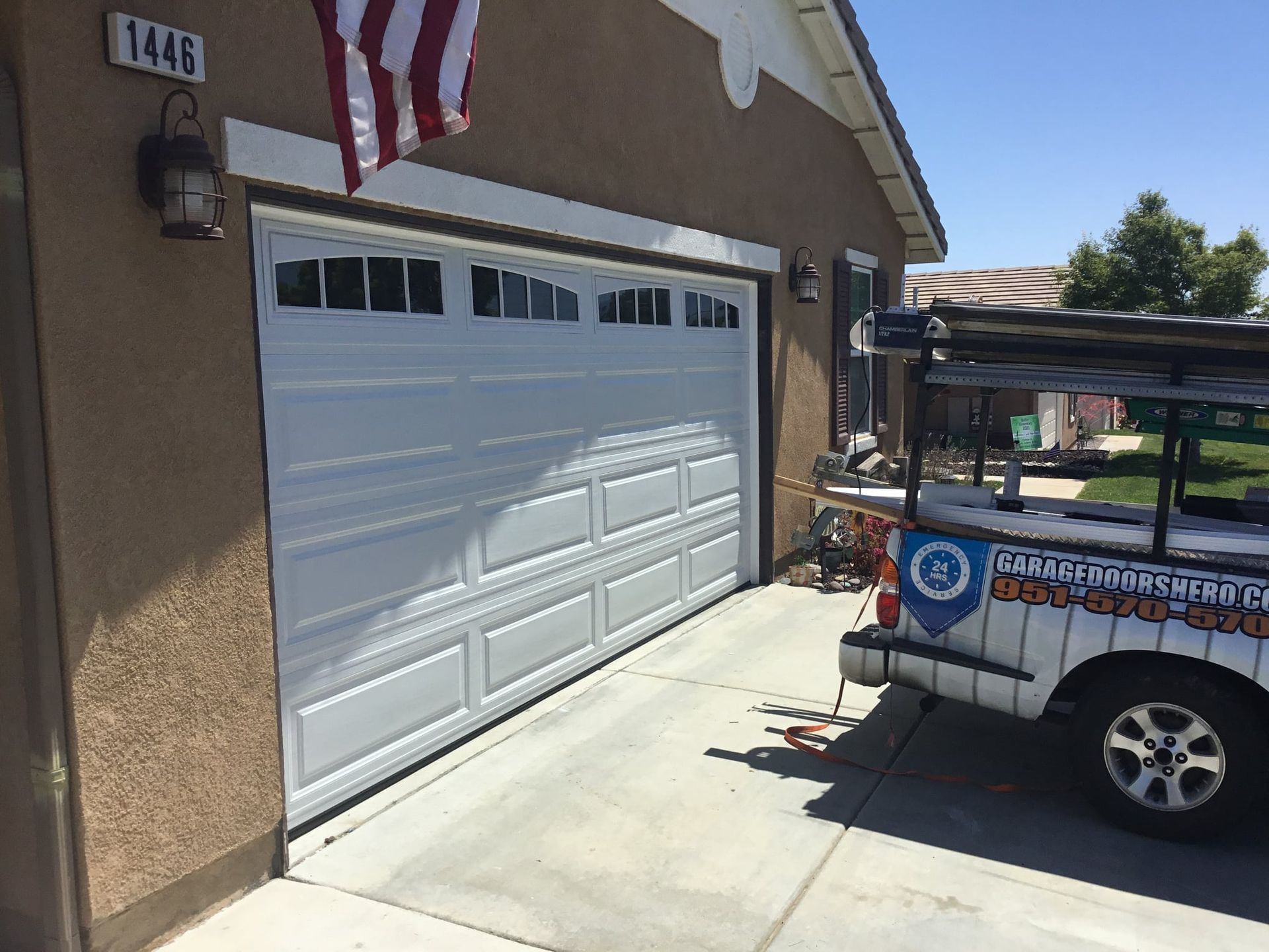 A white truck is parked in front of a garage door.