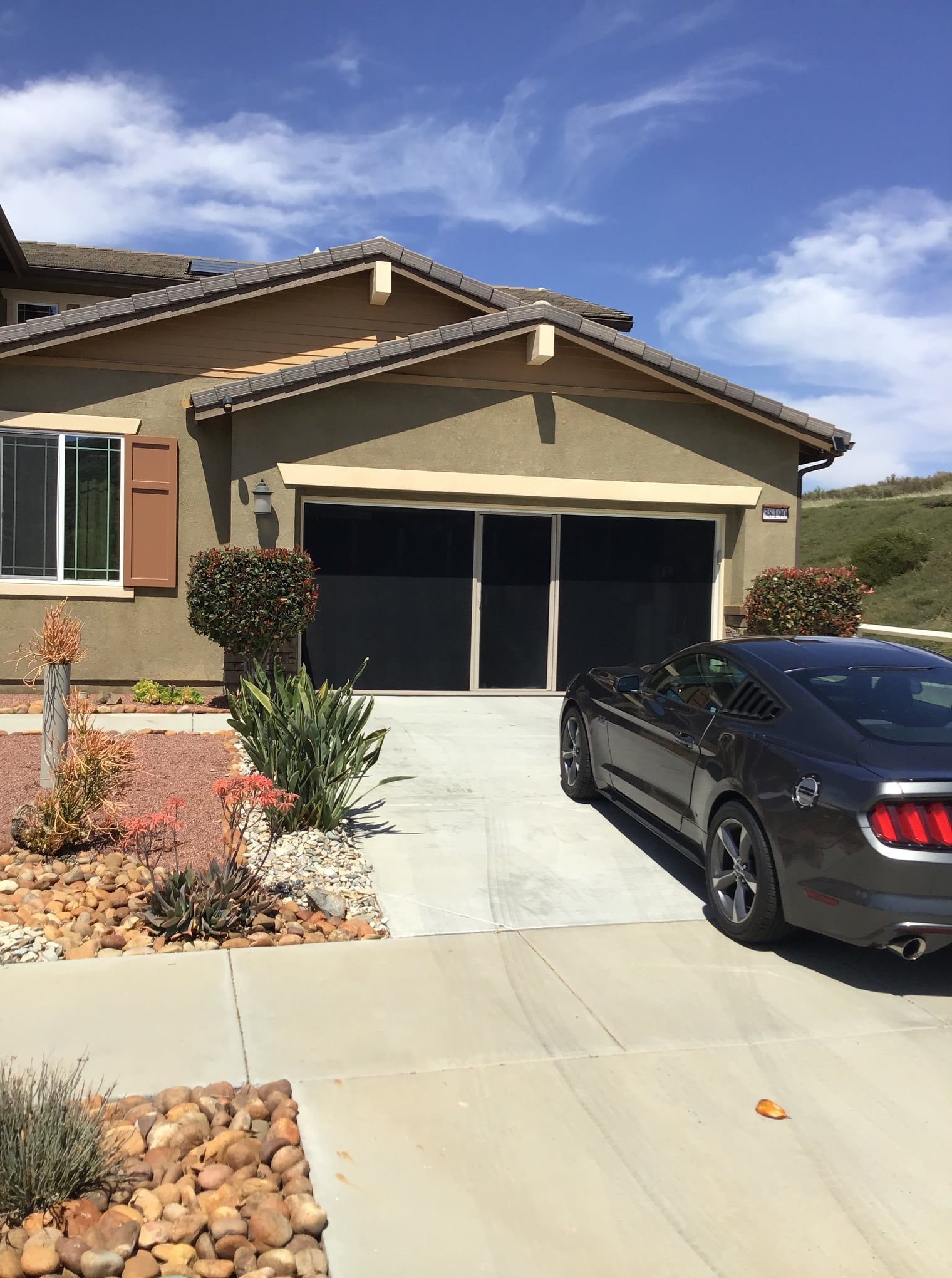 A car is parked in front of a house on a sunny day.