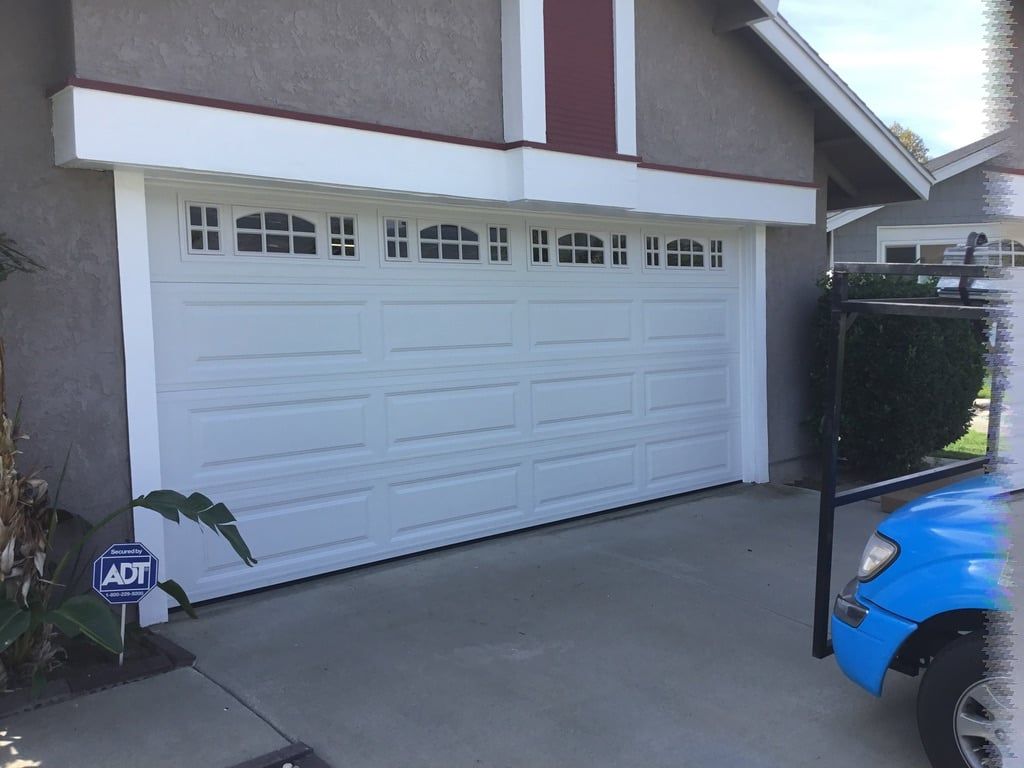 A blue truck is parked in front of a white garage door.
