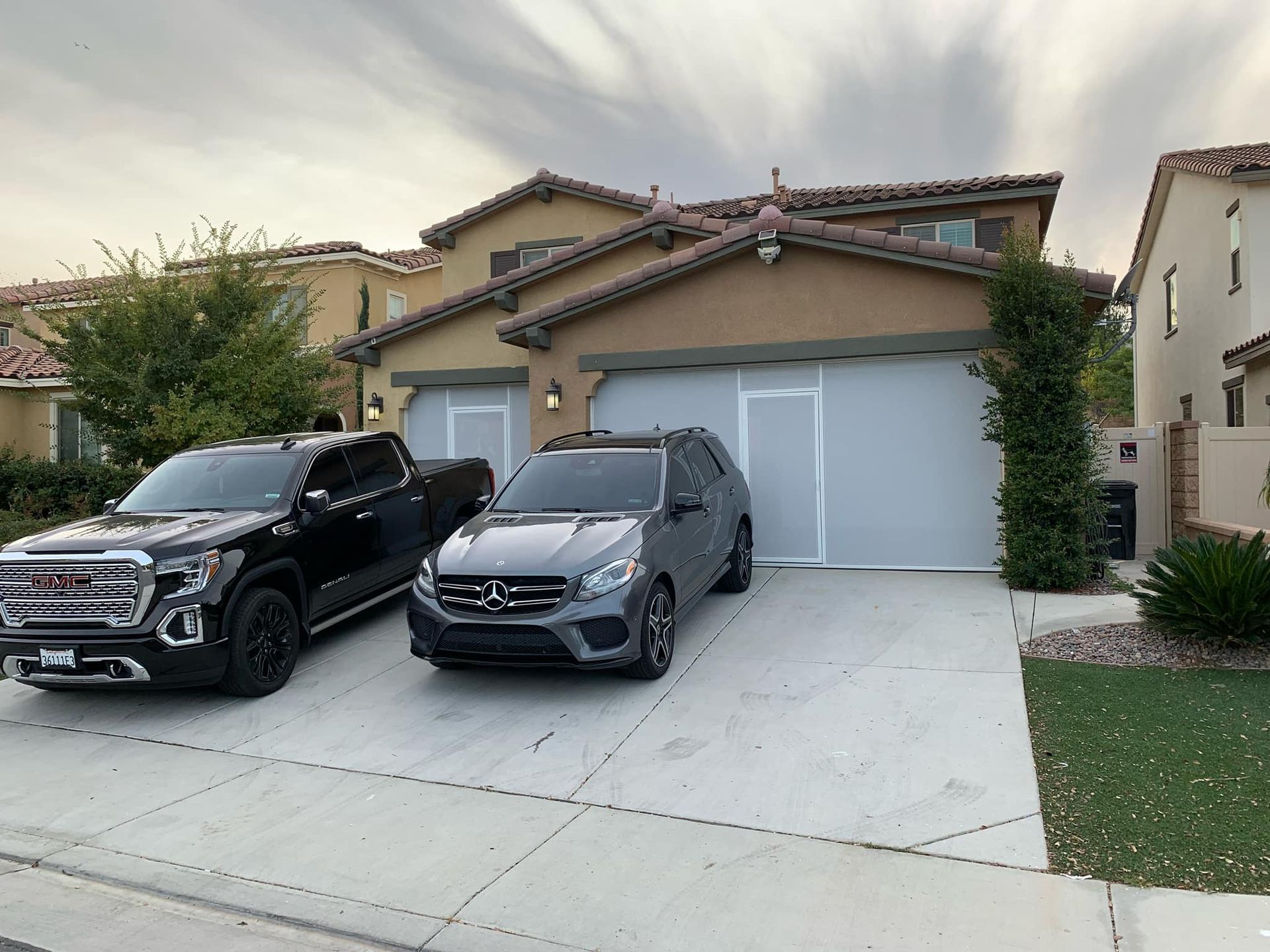 Two cars are parked in front of a house.