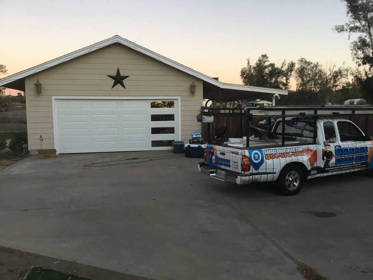 A white truck is parked in front of a garage door.