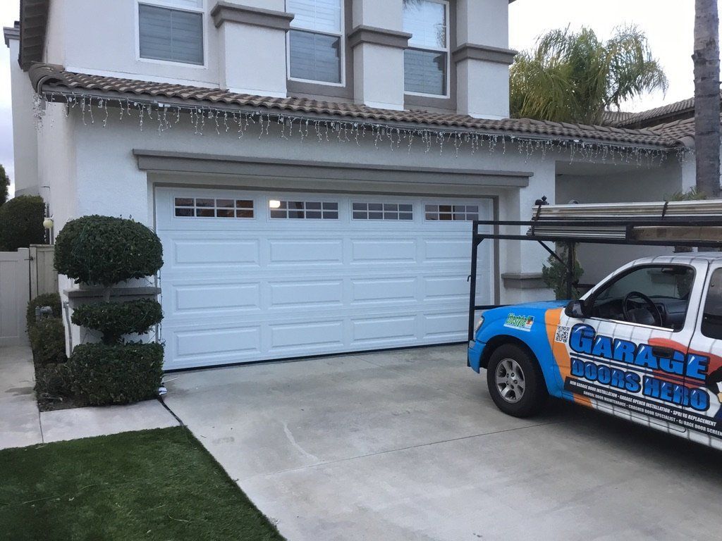 A blue and white truck is parked in front of a white house.