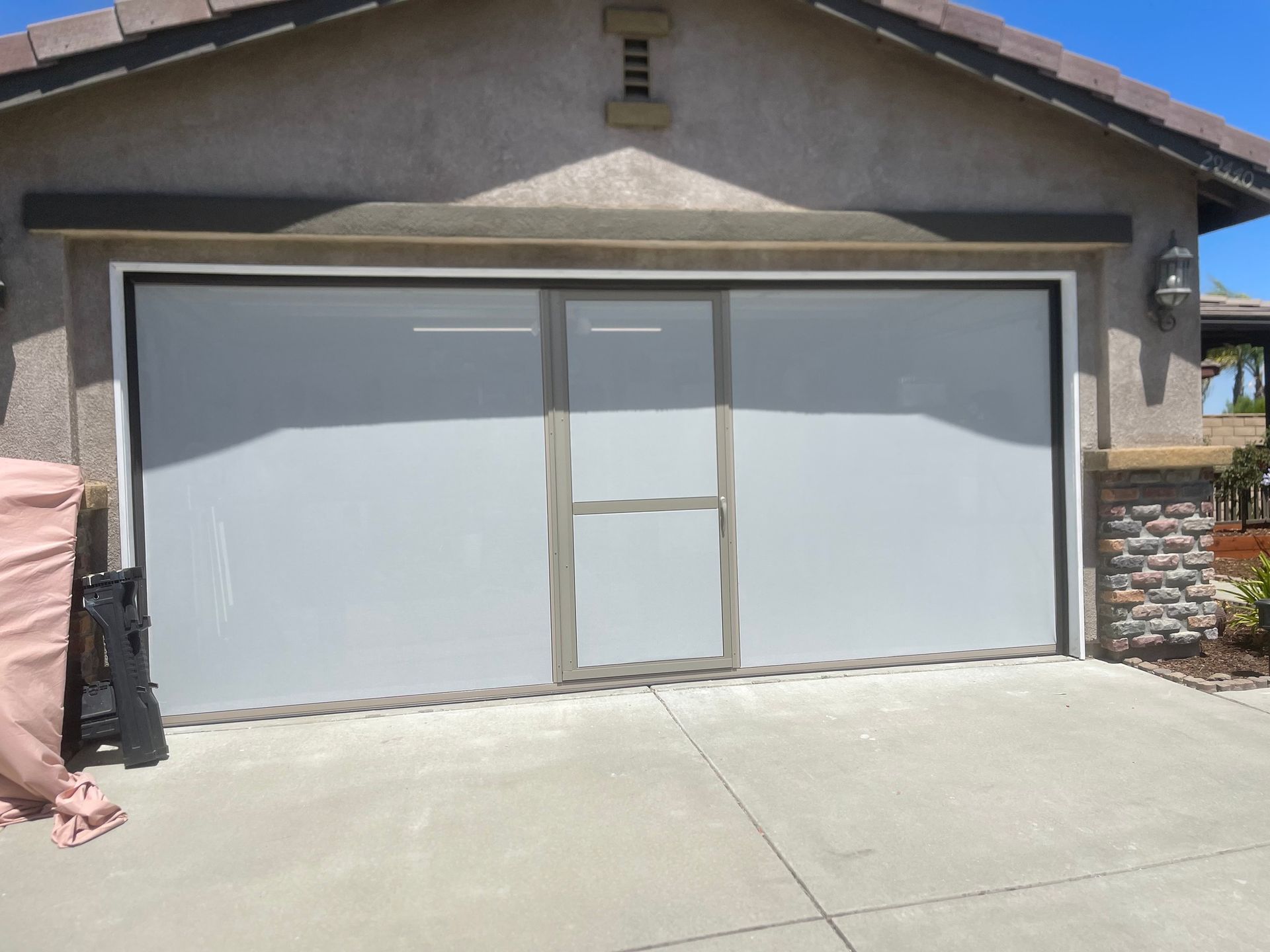 A garage door with a sliding glass door is open in front of a house.