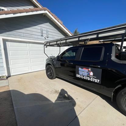 A black van is parked in front of a garage door.