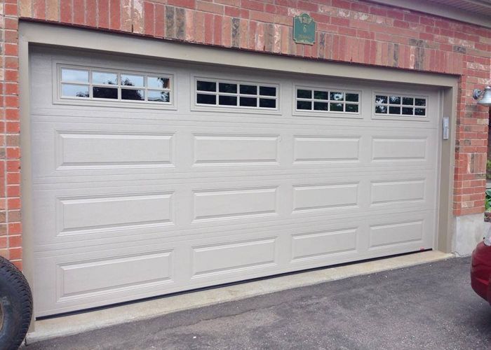 A white garage door is sitting in front of a brick house.