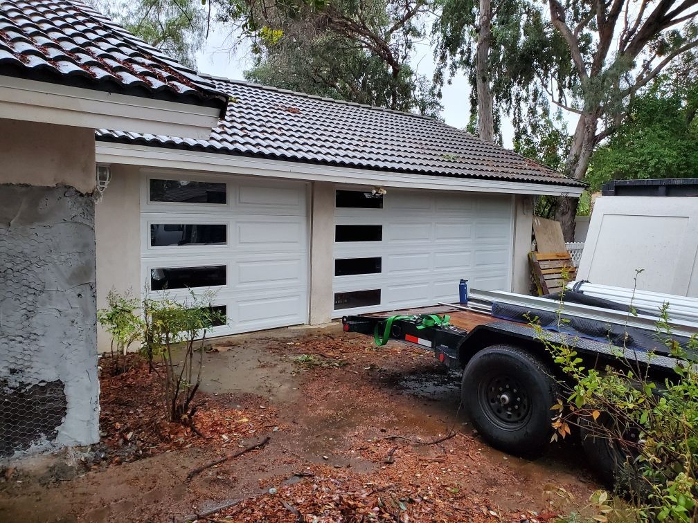 A trailer is parked in front of a garage door.