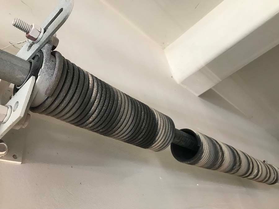 A close up of a garage door spring with a wrench attached to it.