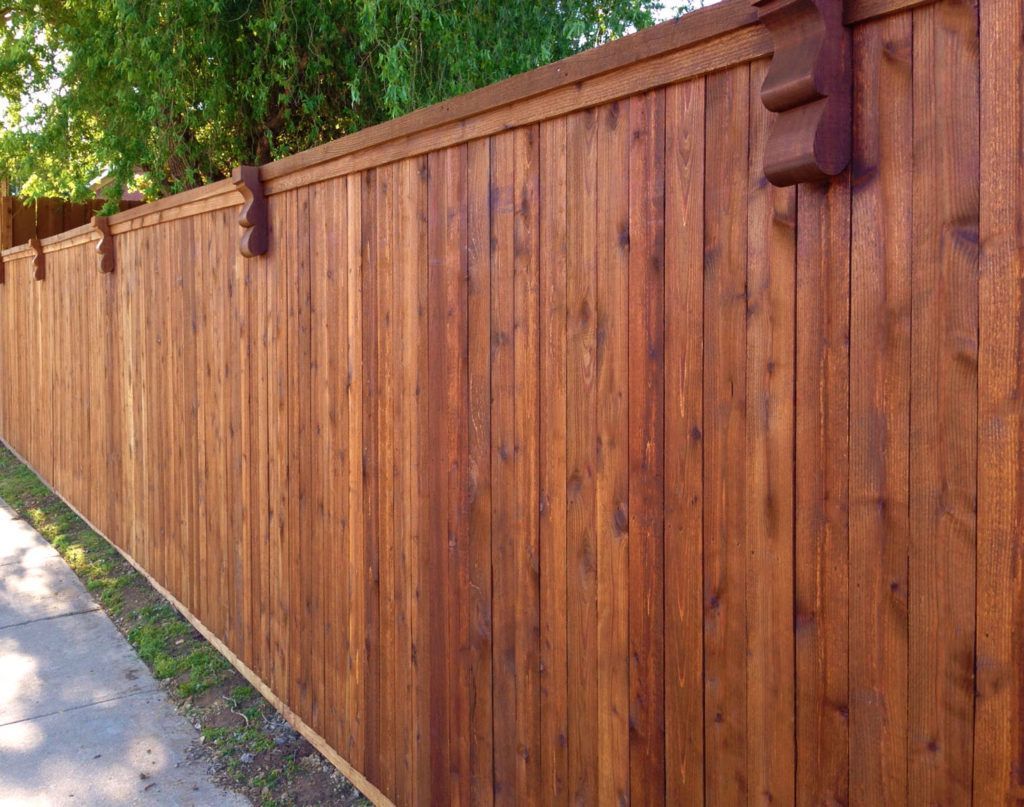 A wooden fence is along the side of a road.
