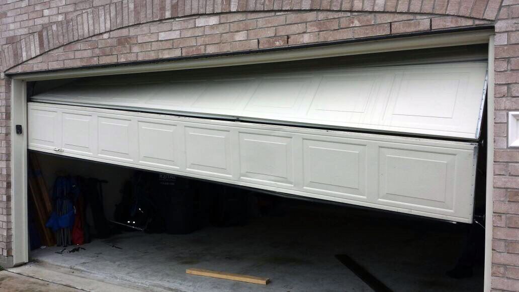 A white garage door is open in a brick building.