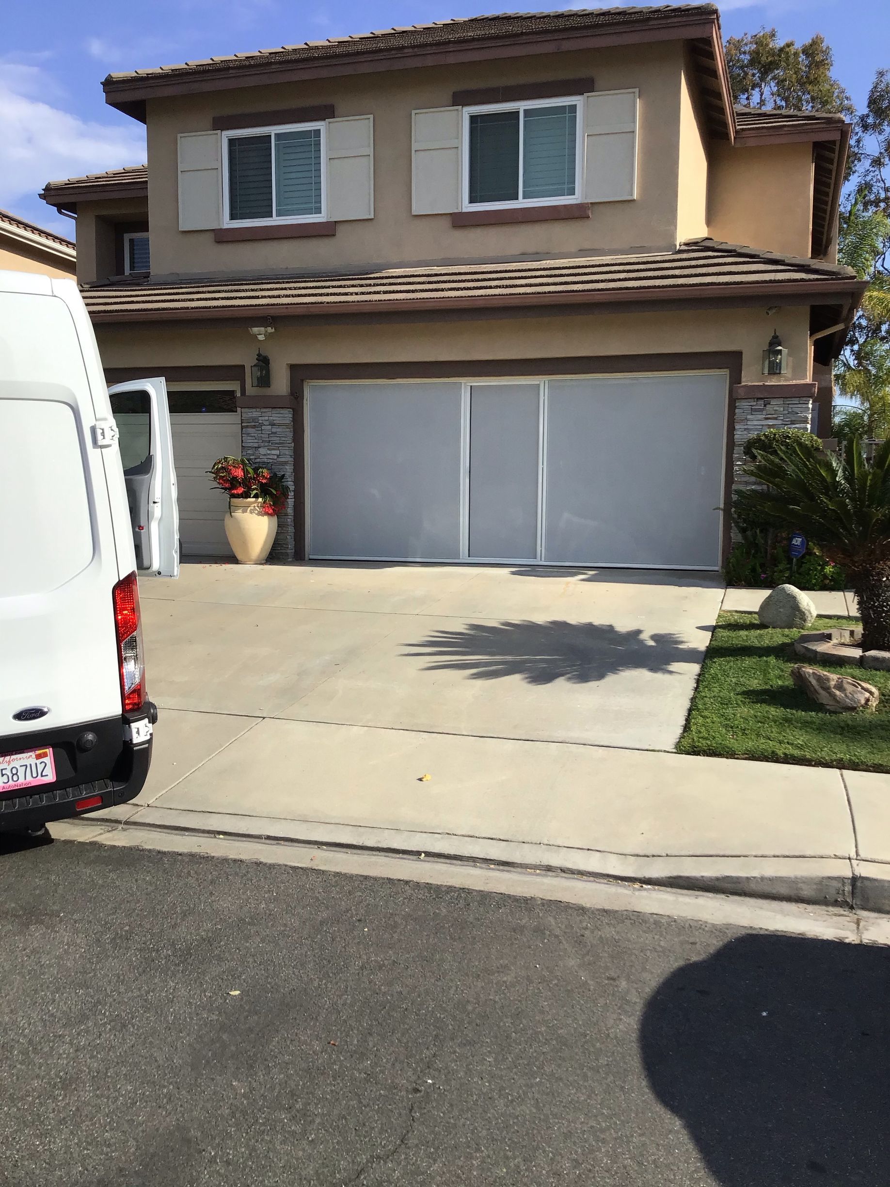 A white van is parked in front of a large house.