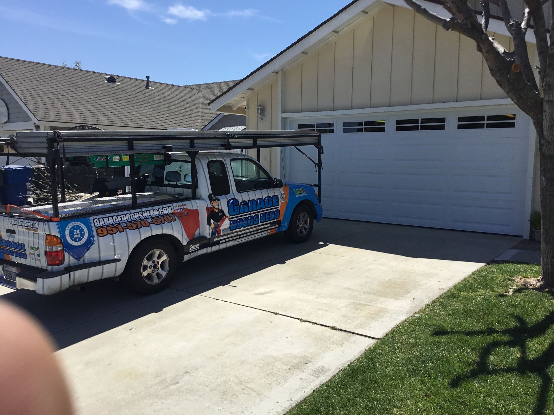 A white truck is parked in front of a white house.
