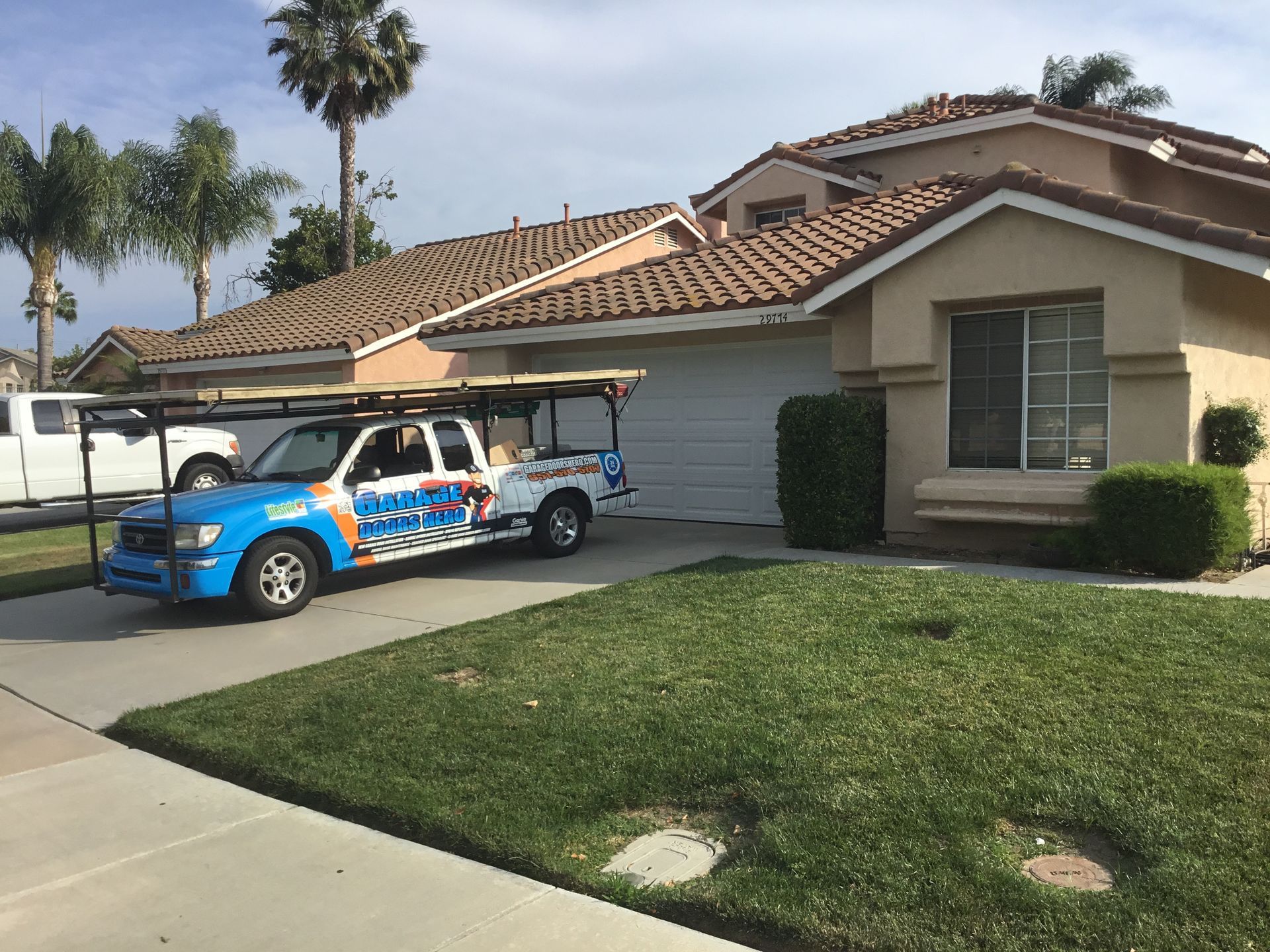 A blue and white truck is parked in front of a house.