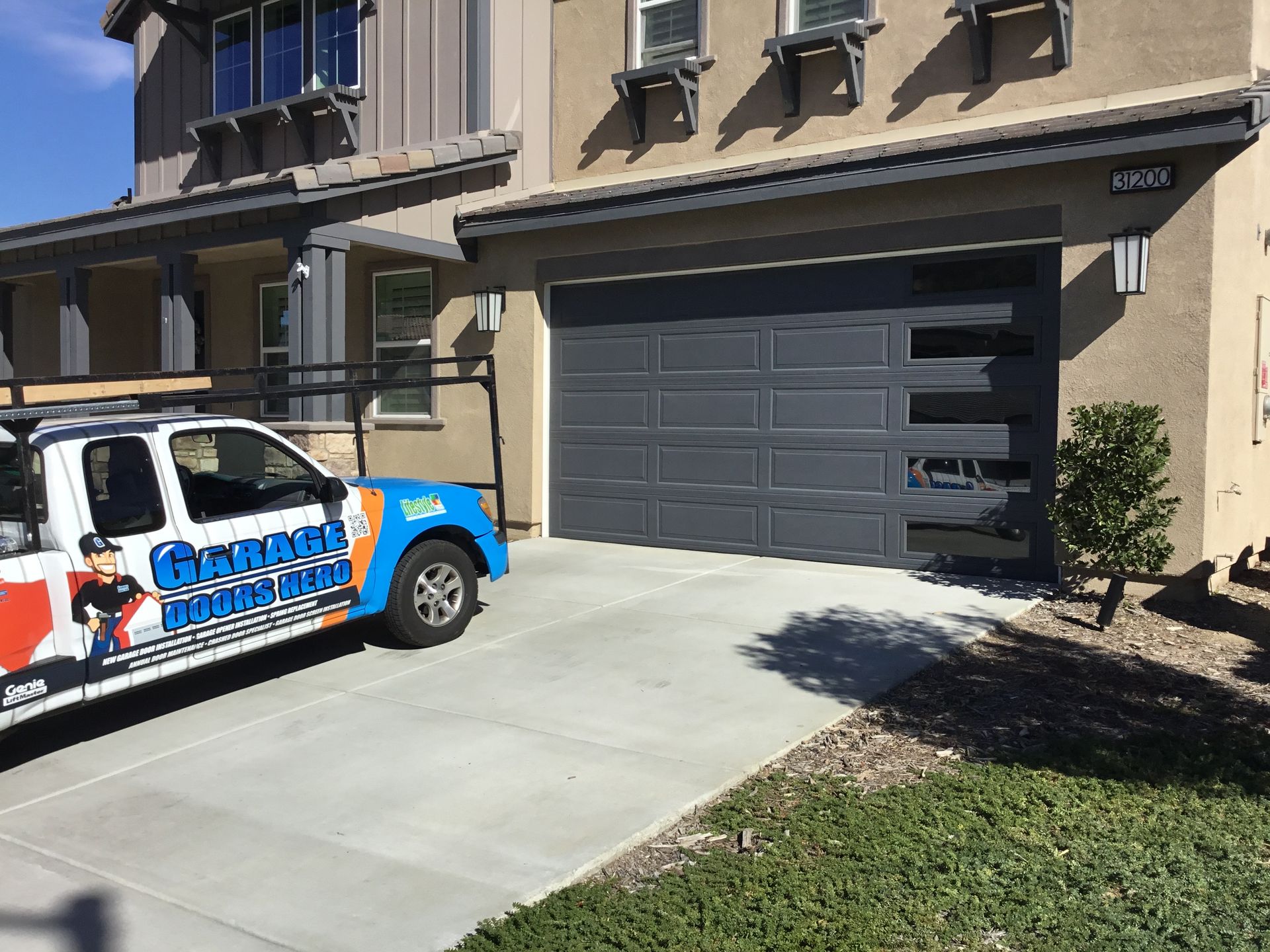 A blue and white truck is parked in front of a house.