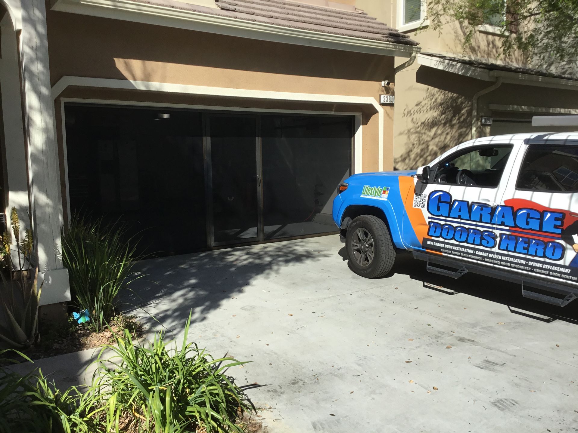 A garage super hero truck is parked in front of a house.