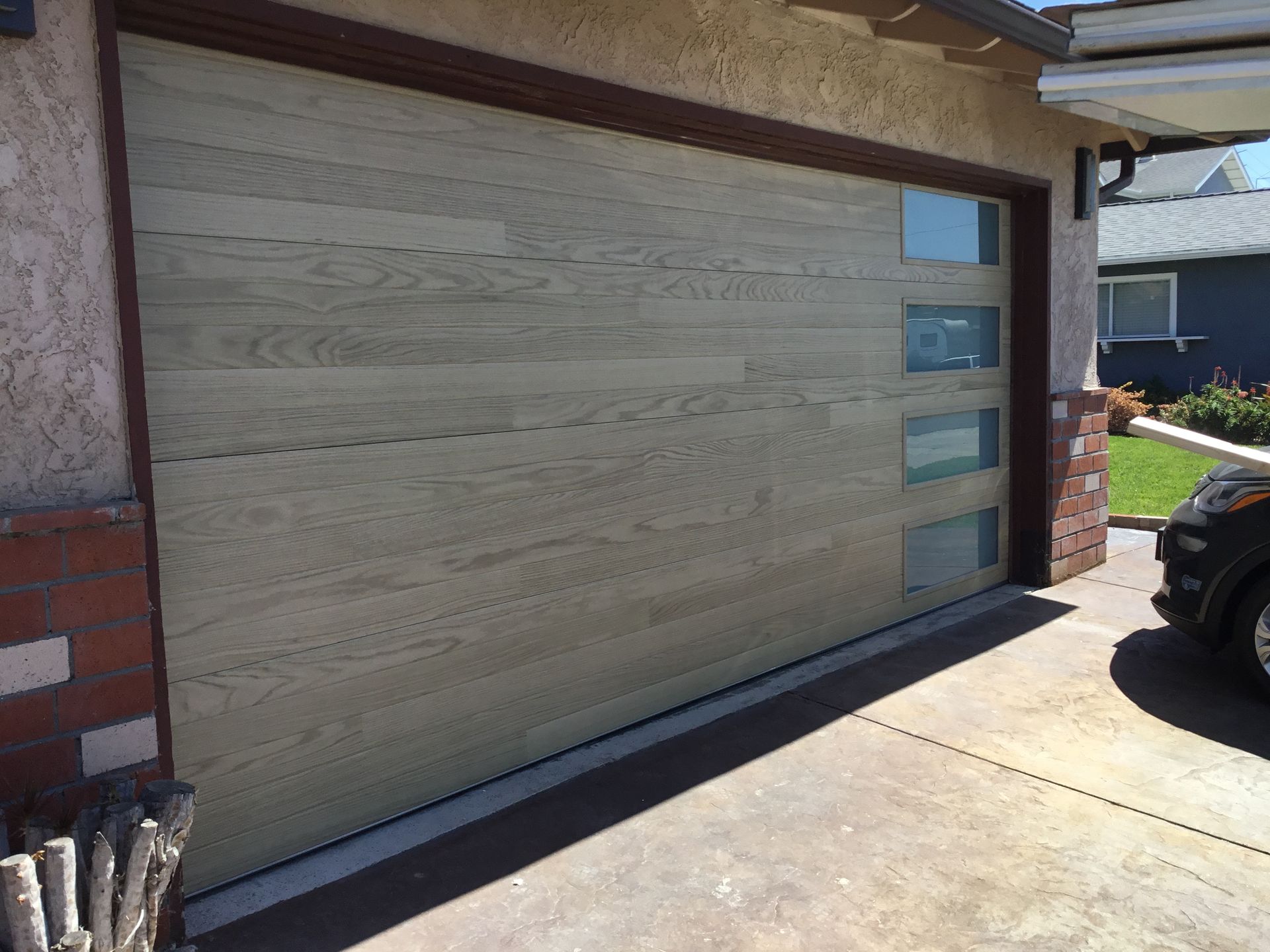 A car is parked in front of a wooden garage door.