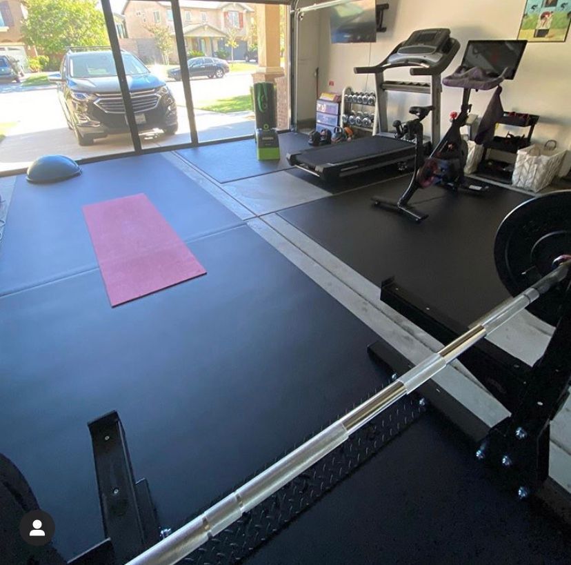 A gym with a treadmill , a bike , a yoga mat and a barbell.