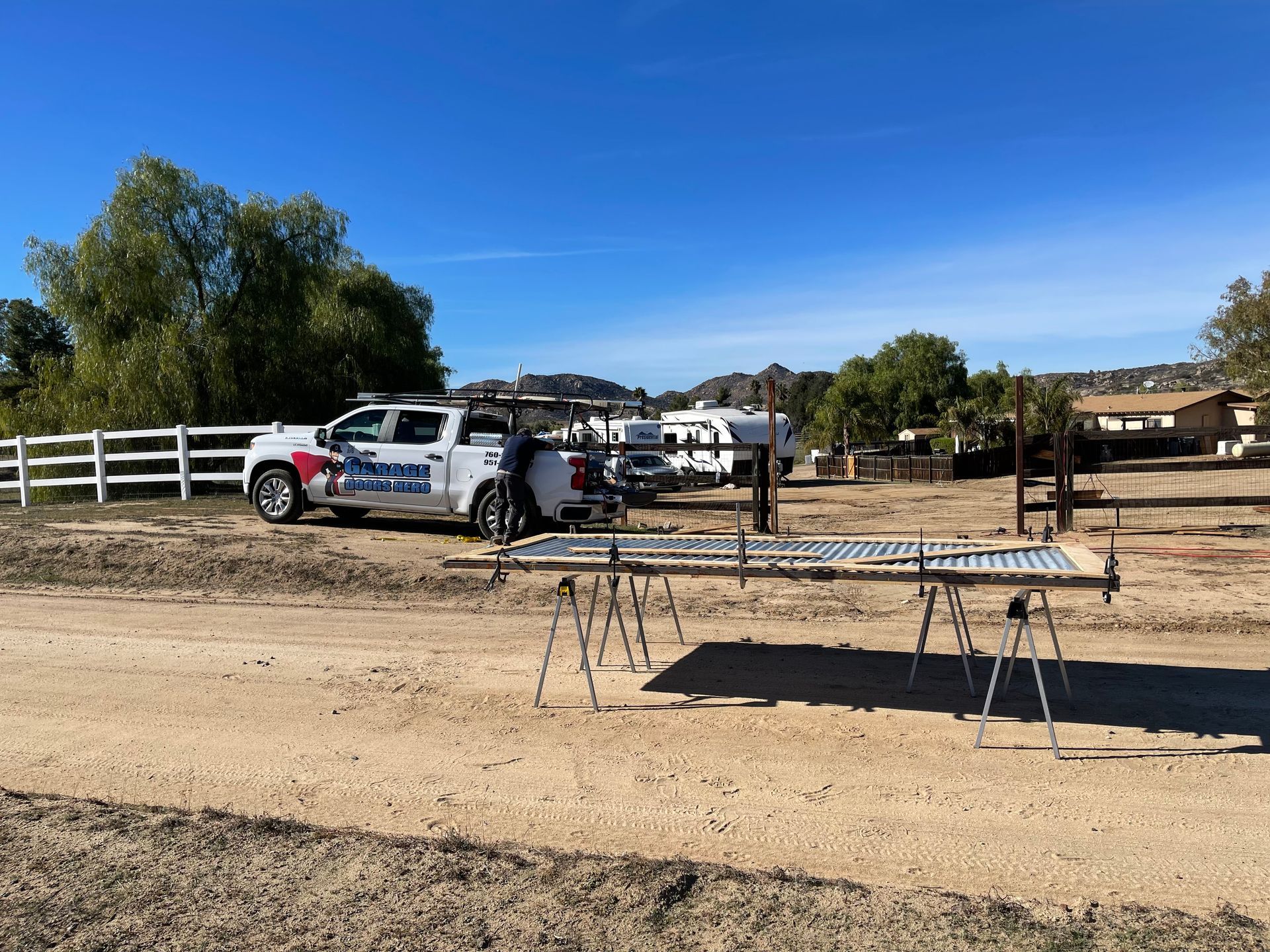 A white truck is parked on the side of a dirt road.