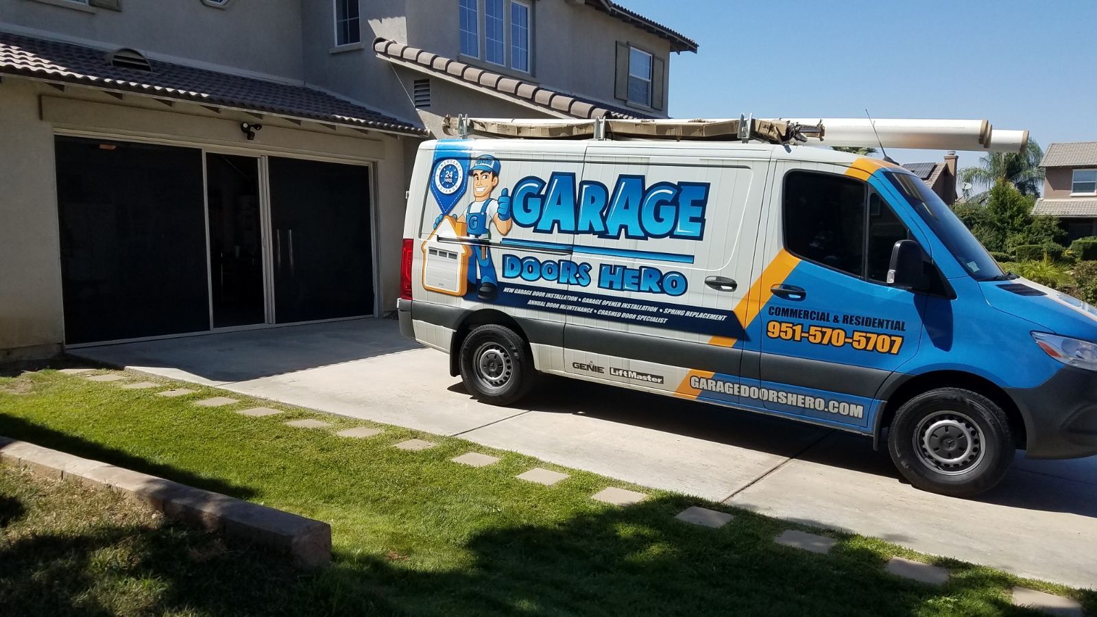 A blue and white van is parked in front of a garage.
