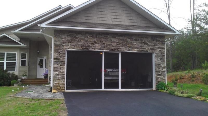 A house with a screened in garage and a car parked in it.