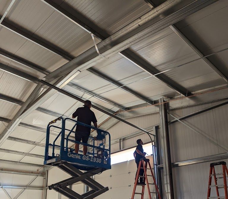 Two men are working on a scissor lift in a building