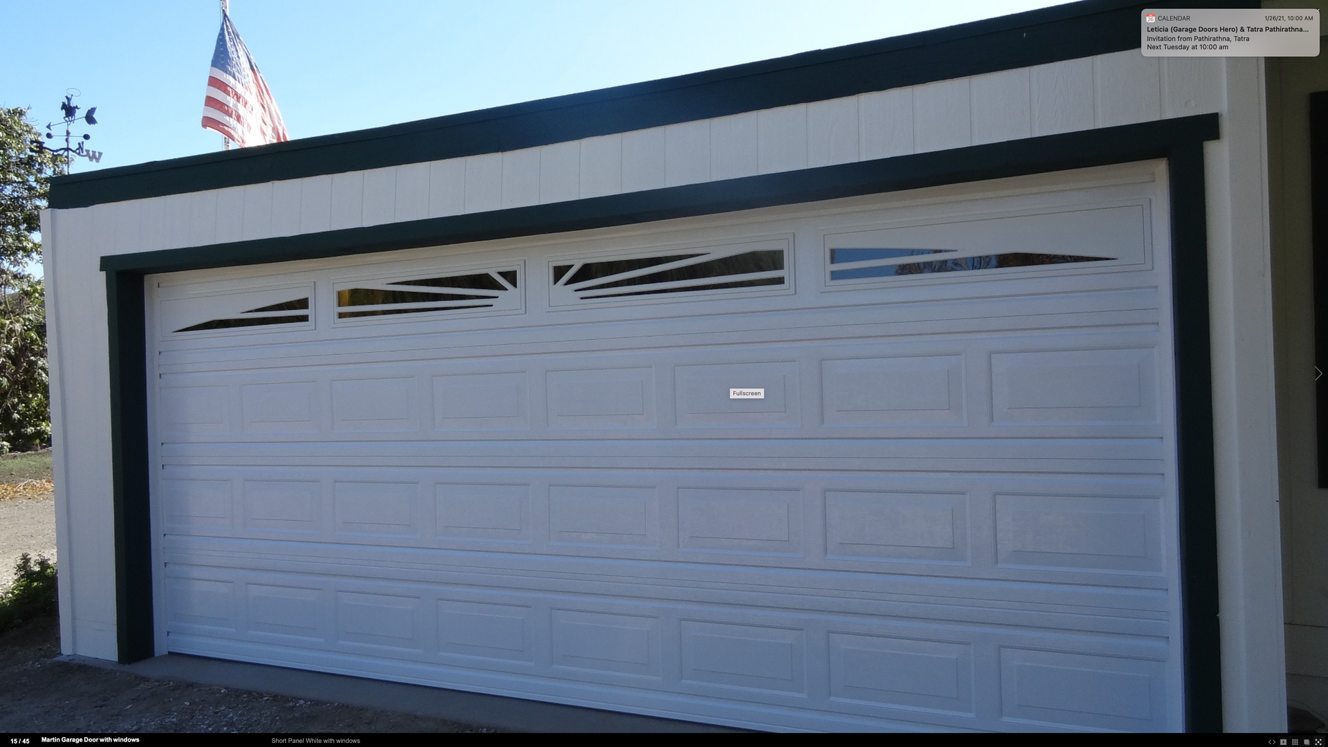 A white garage door with a black trim and an american flag in the background