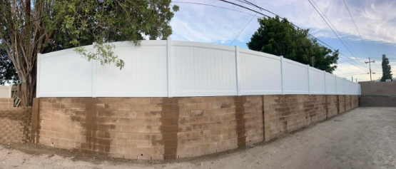 A white fence is surrounded by a brick wall.