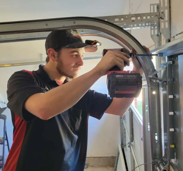 A man is working on a garage door with a drill