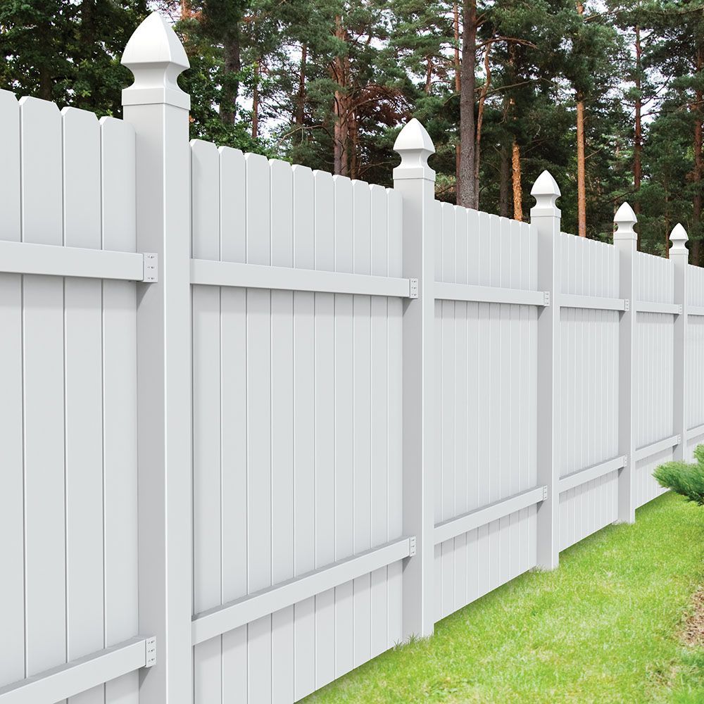 A white wooden fence with trees in the background