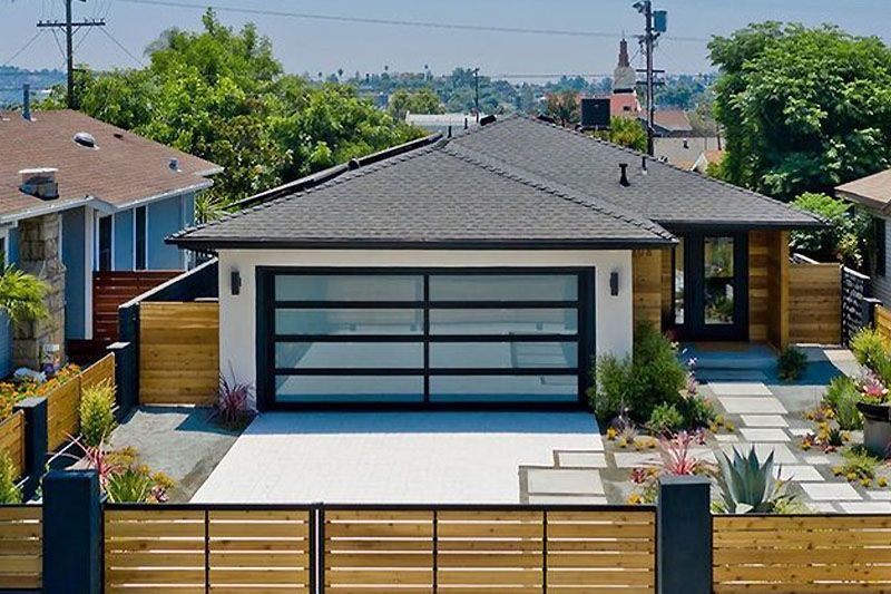 An aerial view of a modern house with a large garage door and a wooden fence.