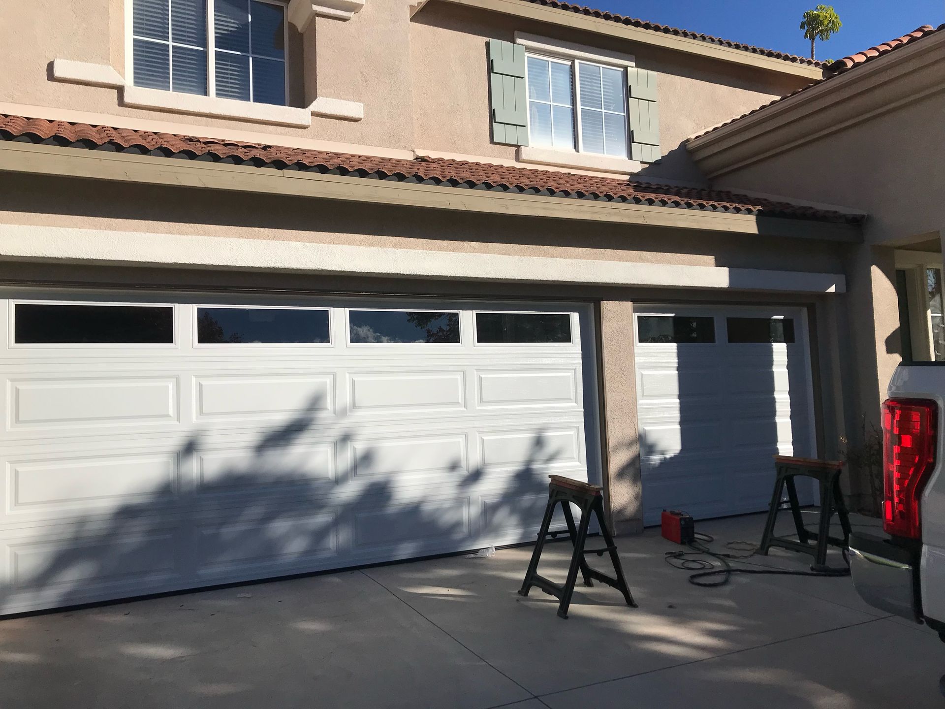 A white garage door is being installed in front of a house.