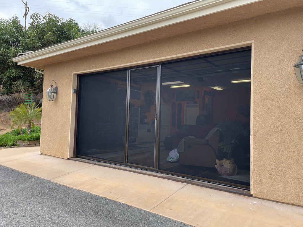 A house with a screened in garage door and sliding glass doors.