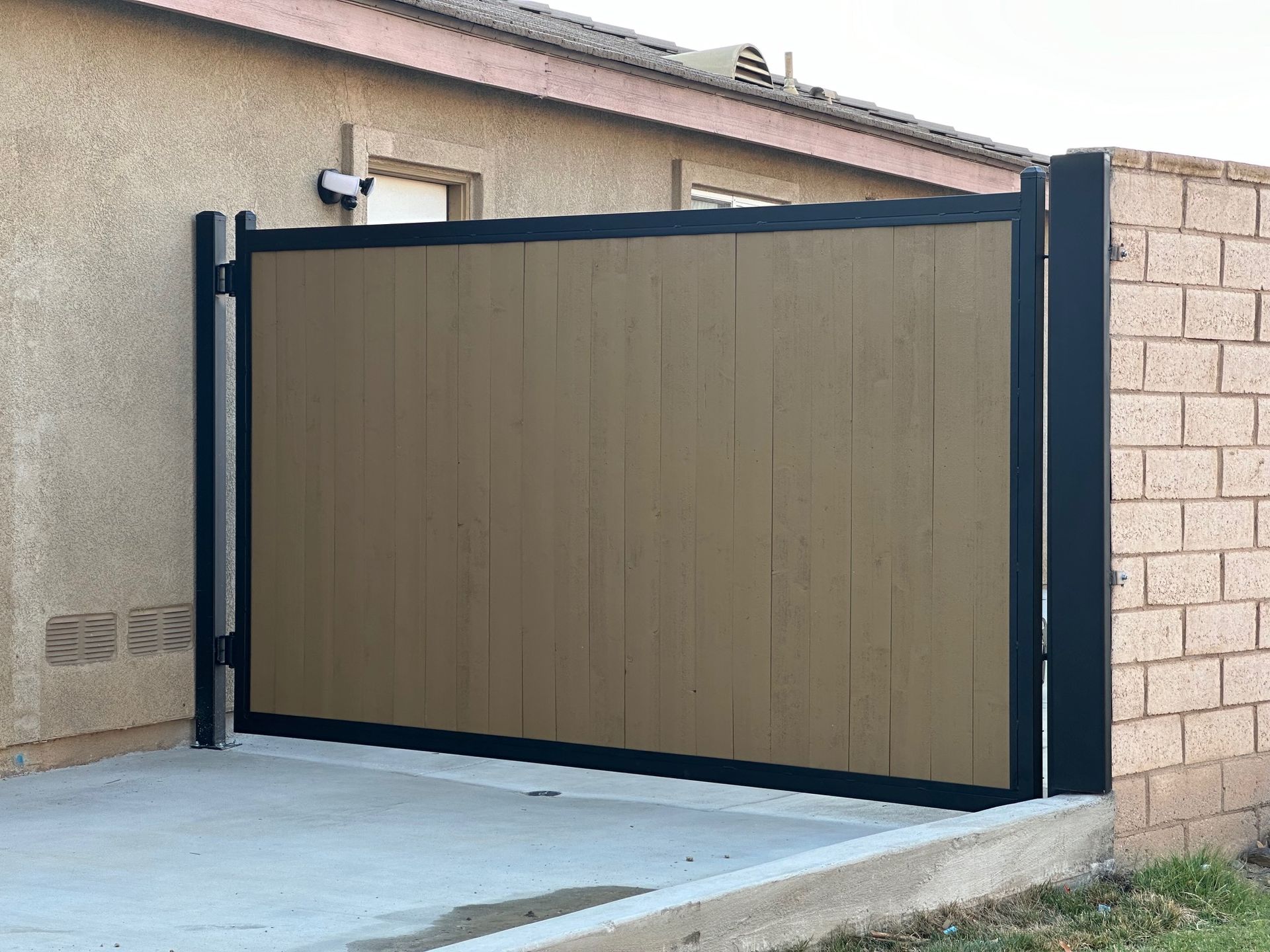 A wooden gate is sitting in front of a brick wall.