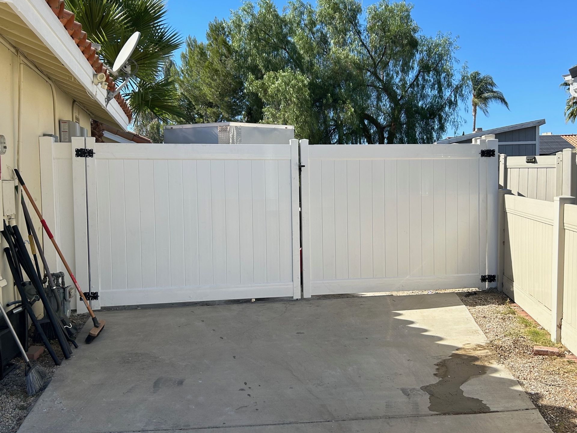 A white fence is sitting in a driveway next to a house.