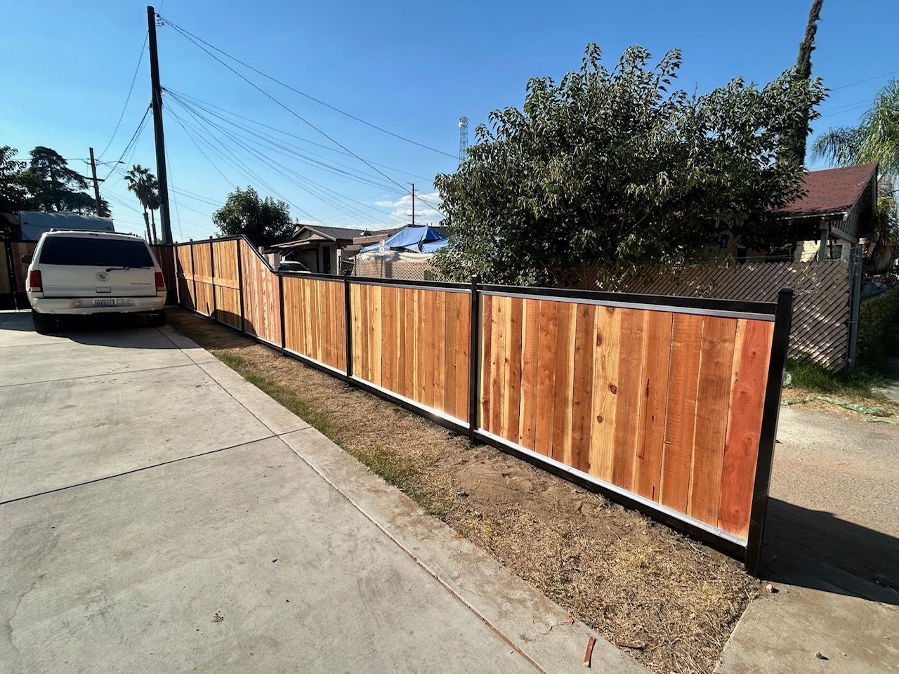 A white suv is parked next to a wooden fence.