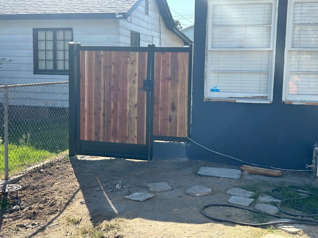 A wooden gate is sitting in front of a blue house.